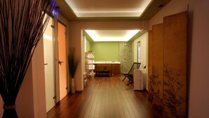 Un pasillo con suelo de madera, mostrador de recepción, pared verde y una gran decoración de bambú.