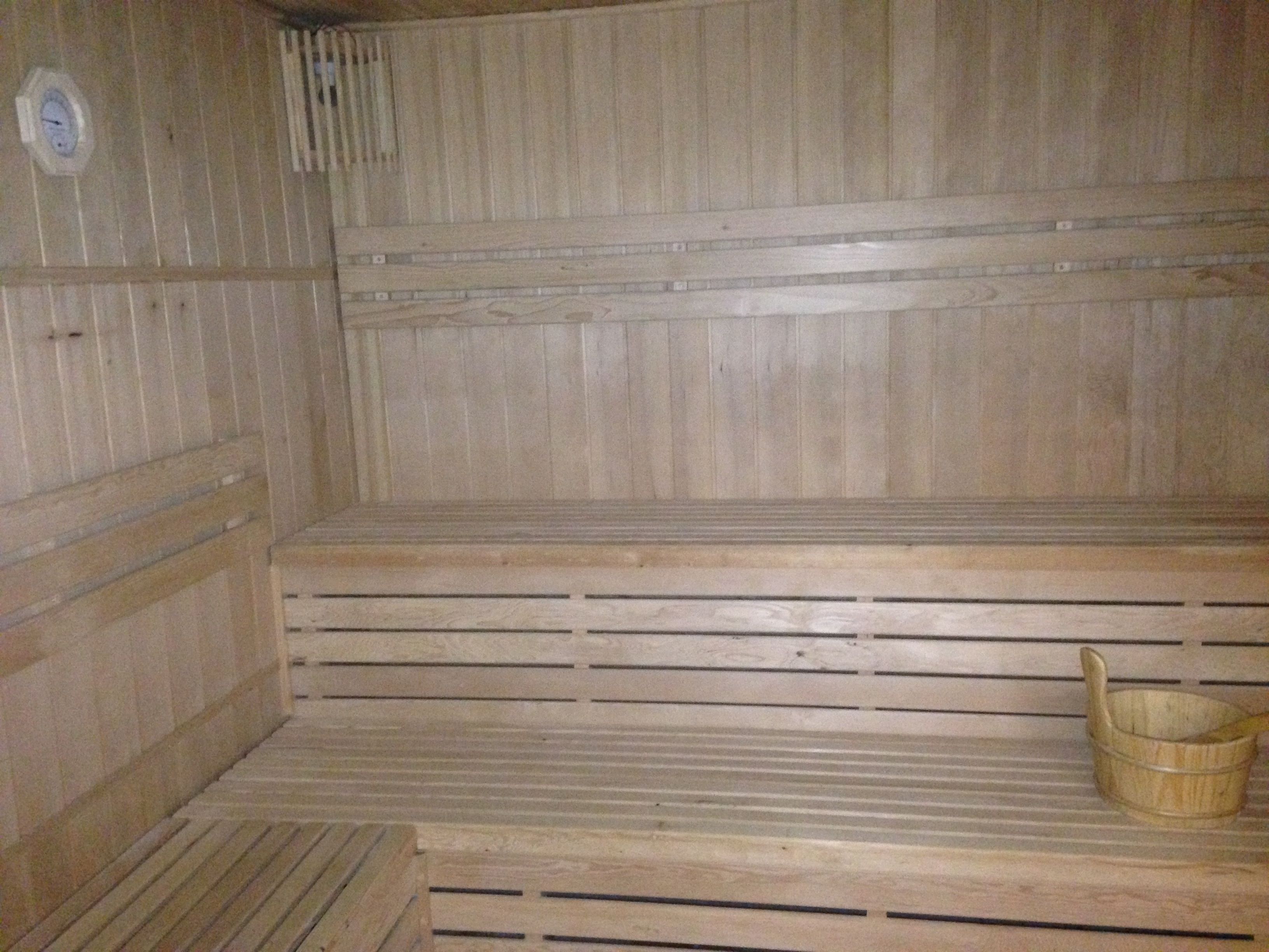 Een sauna met houten banken en een houten emmer.