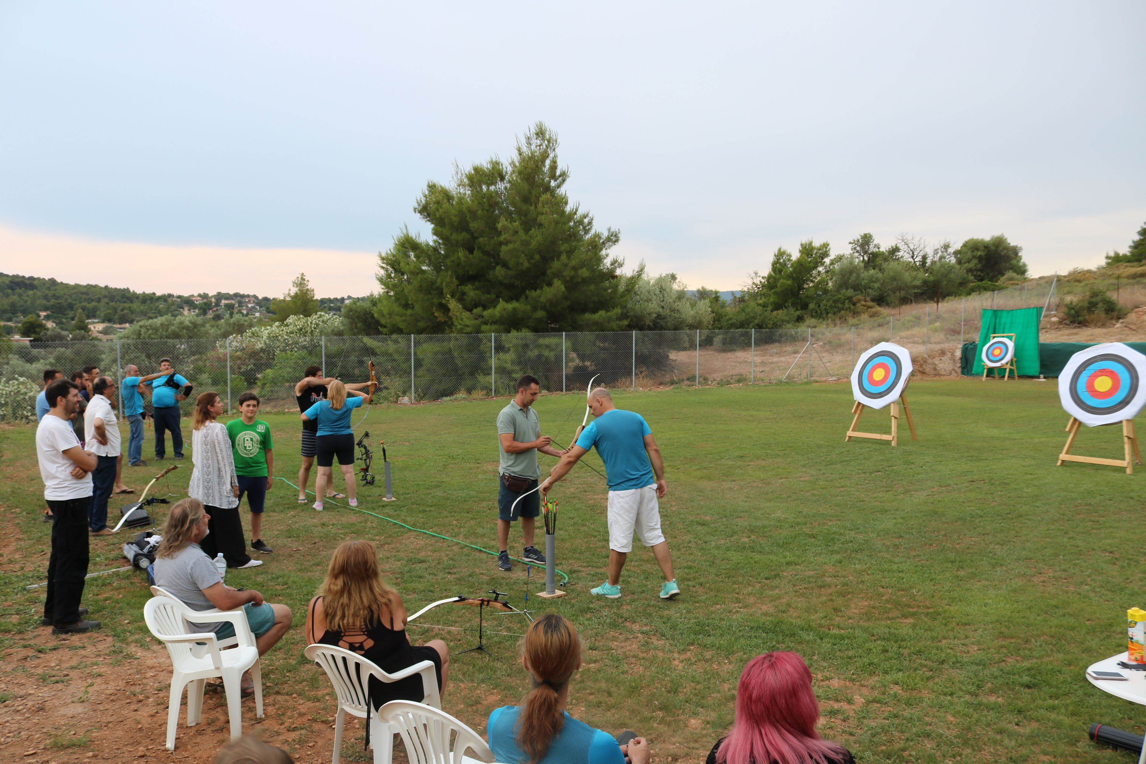 An outdoor setting with people engaged in an activity, possibly a game or demonstration, with targets and a green screen in the background.
