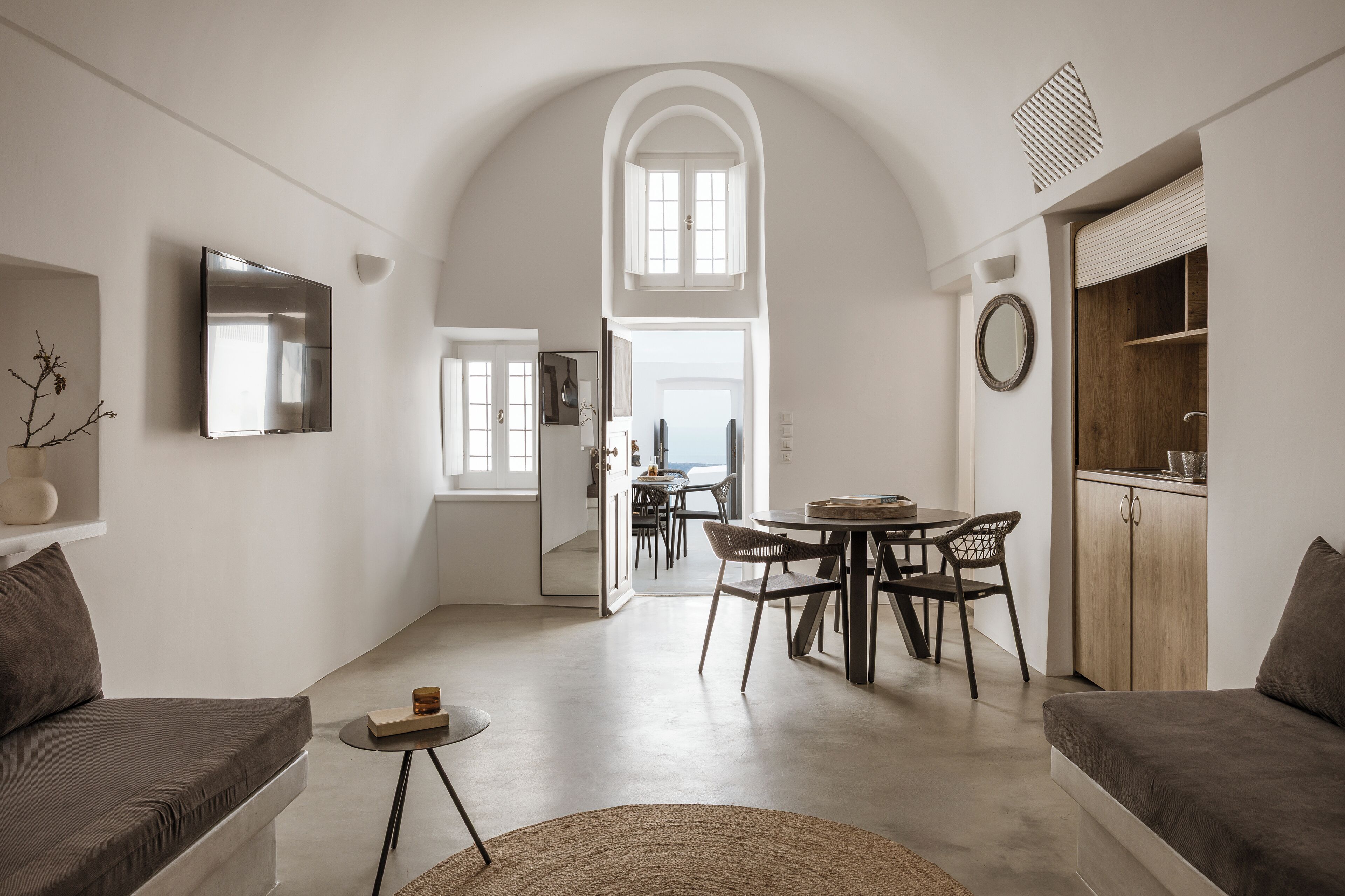 A modern interior with a dining area, sofas, and a kitchen.