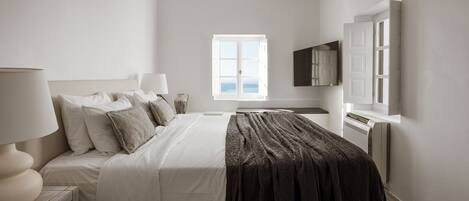 A modern bedroom with a bed, bedside lamps, a TV, and a window with a view.