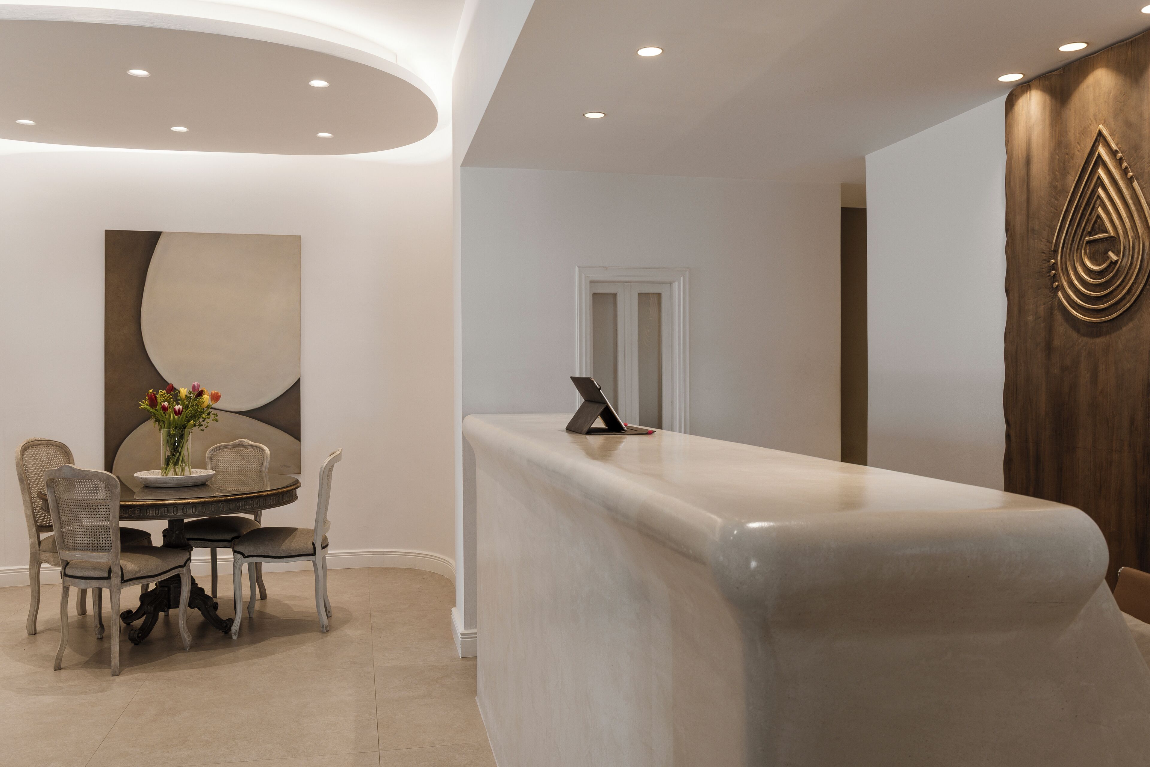 A reception area with a marble counter, a modern chair design, and a wall-mounted decorative piece.