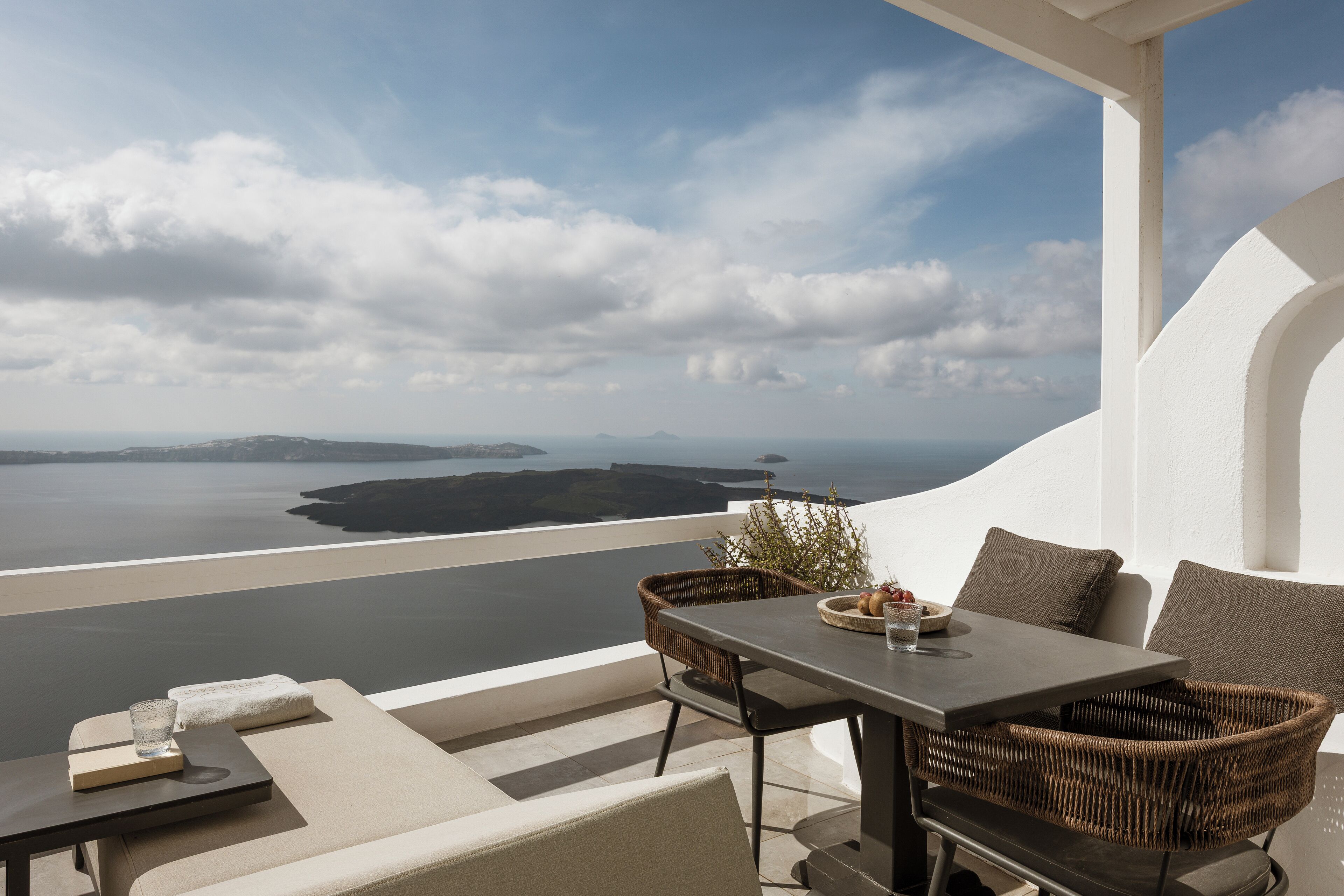 Eine Terrasse mit Tisch und Stühlen, mit Blick auf ein Gewässer und die Ferne.
