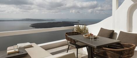 Eine Terrasse mit Tisch und Stühlen, mit Blick auf ein Gewässer und die Ferne.