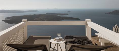 Een balkon met een tafel, twee stoelen en uitzicht op zee en eilanden.