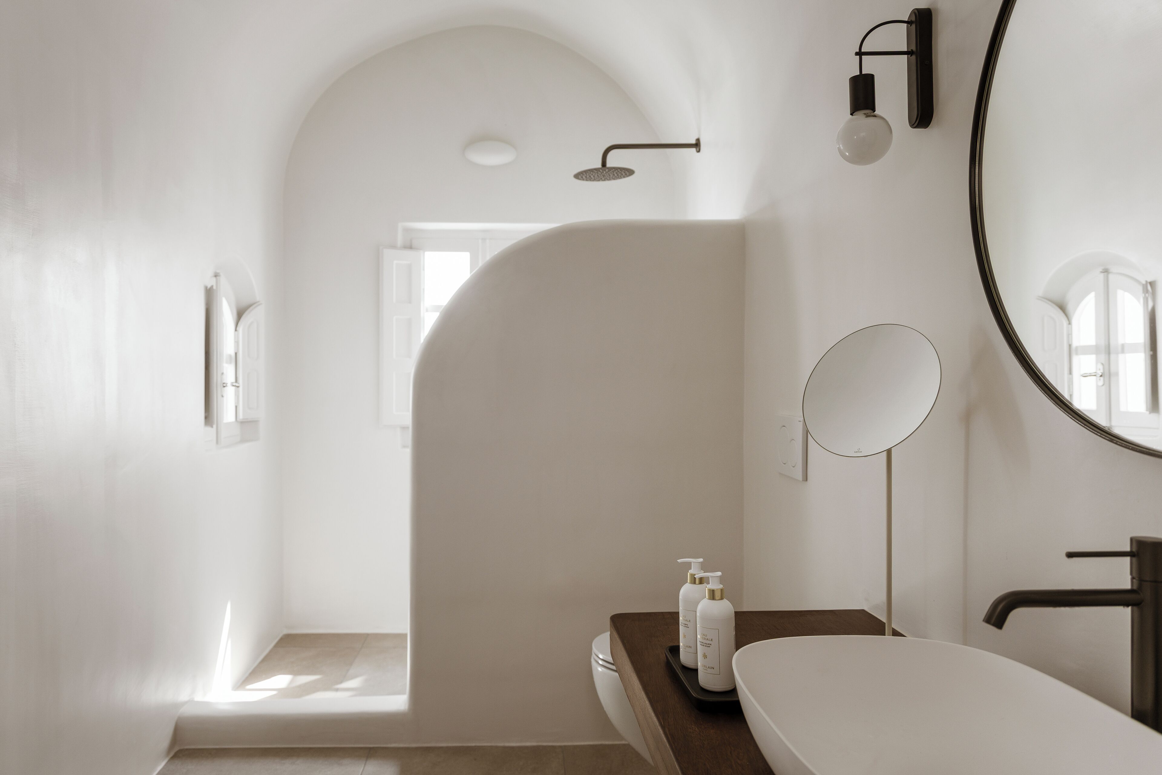 A modern bathroom with a freestanding bathtub, a round mirror, and a showerhead.