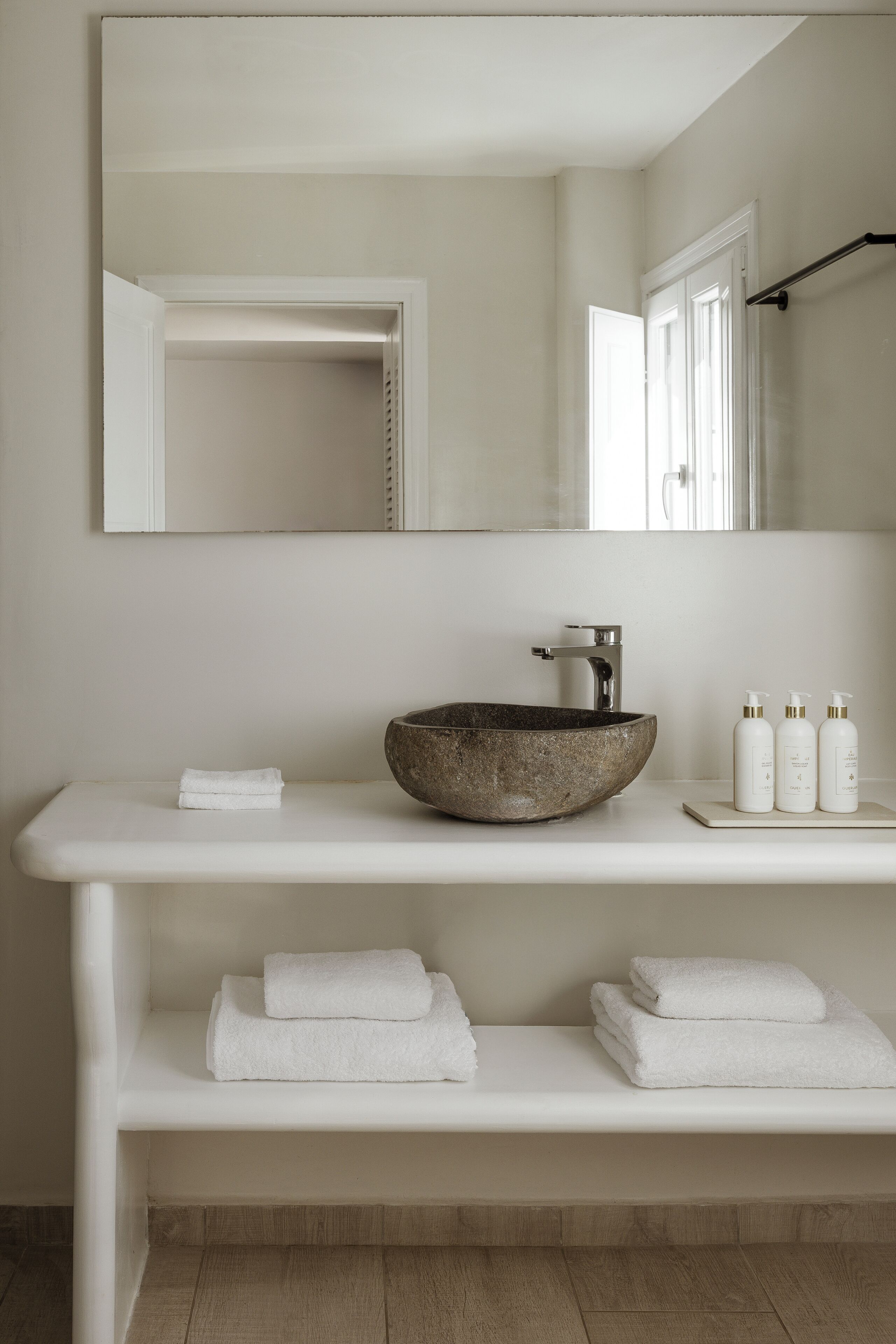 A bathroom with a large mirror, a vessel sink, and a towel rack.