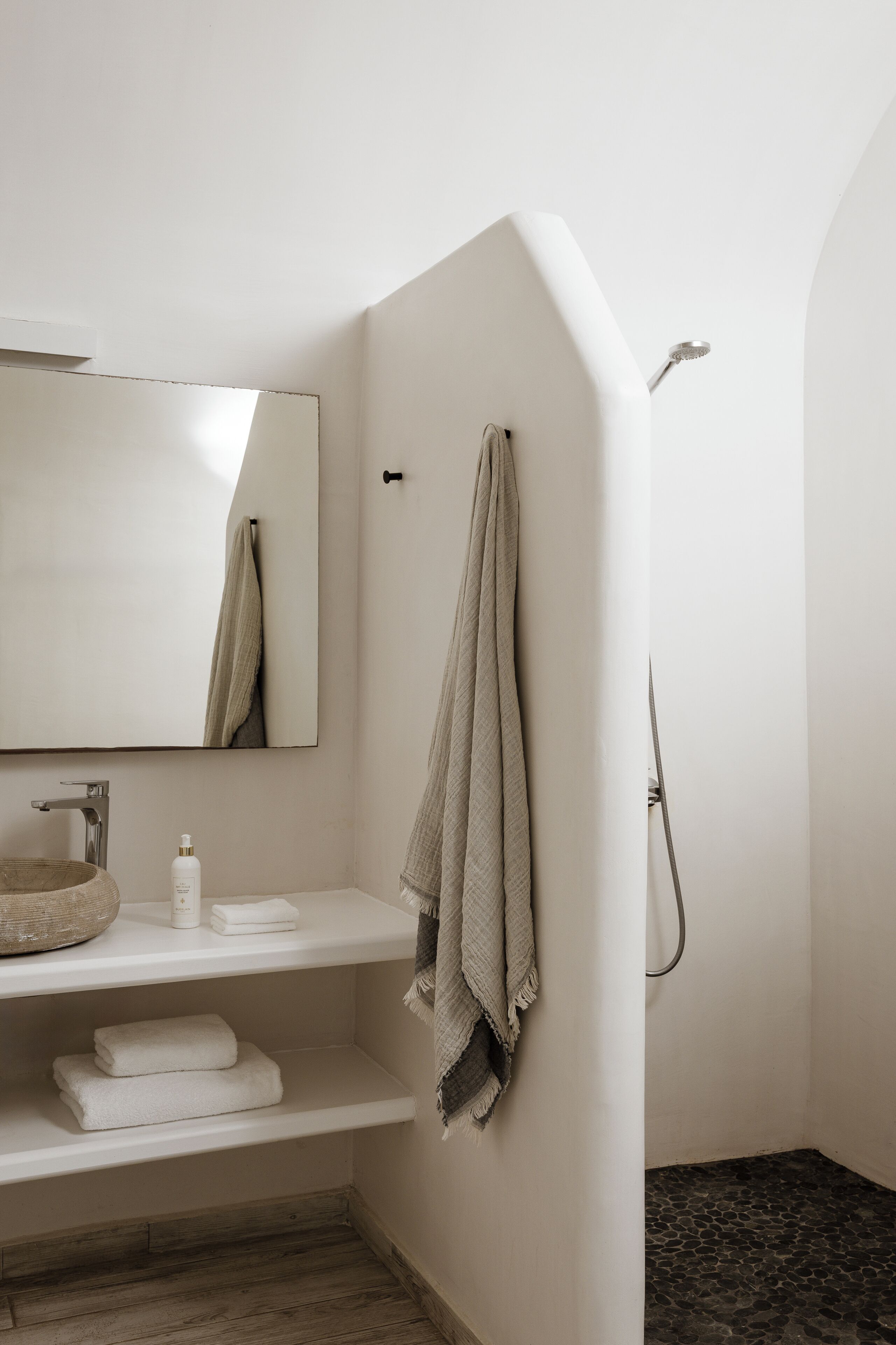 A bathroom with a sink, mirror, towel rack, and shower.