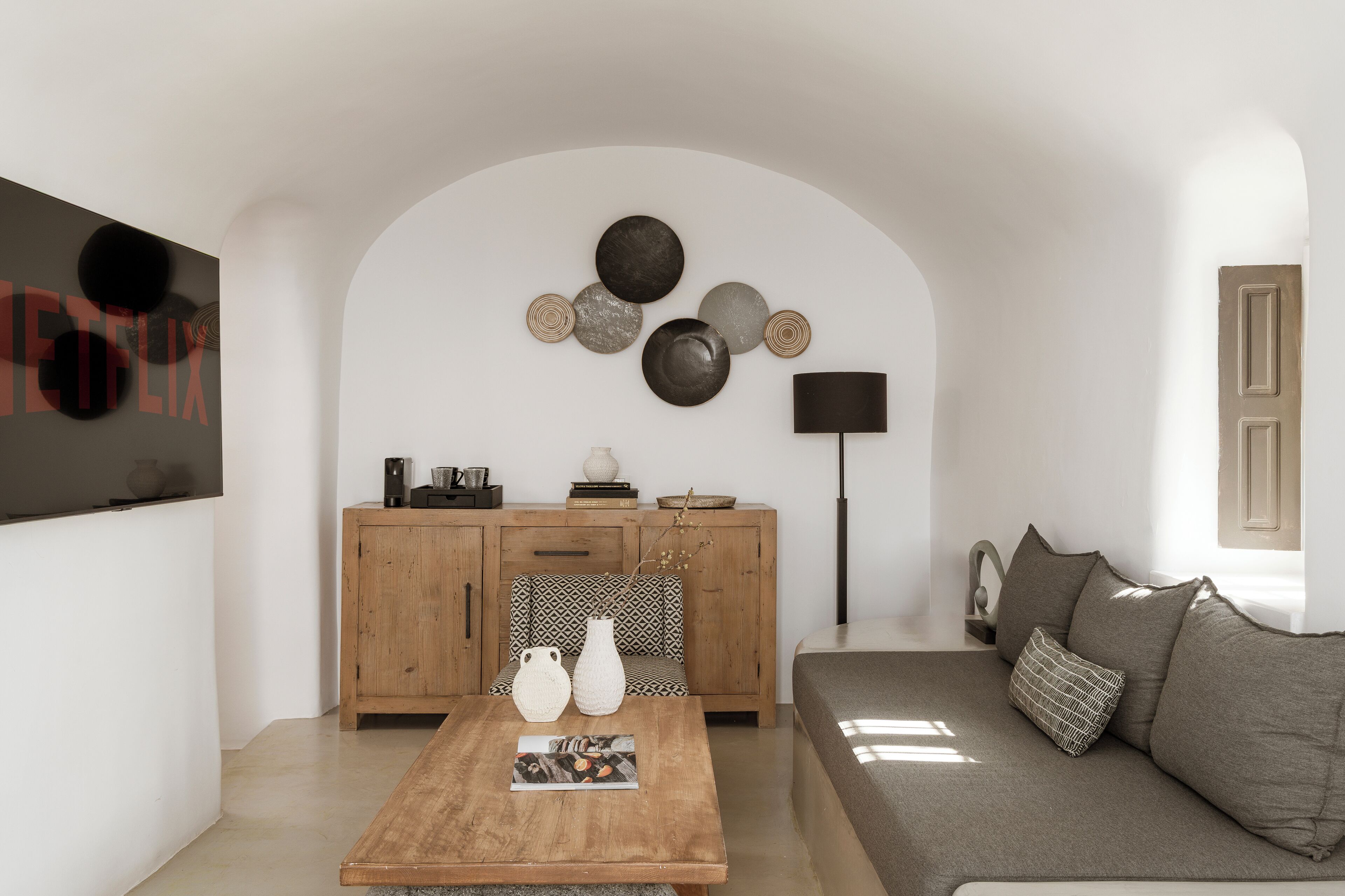 Una sala de estar moderna con una mesa de centro de madera, un sofá, un armario y decoración en la pared.