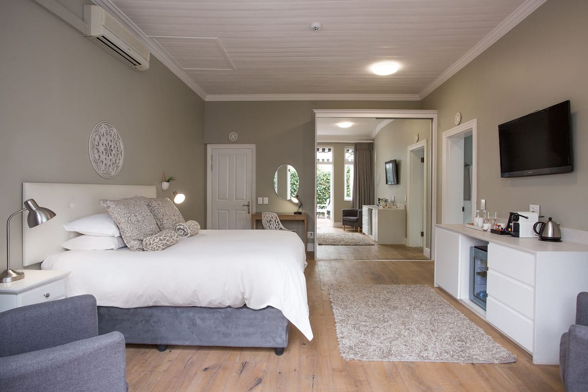 Ein Schlafzimmer mit Bett, Nachttischen, Schreibtisch, Stuhl, Fernseher und einer Küchenzeile.