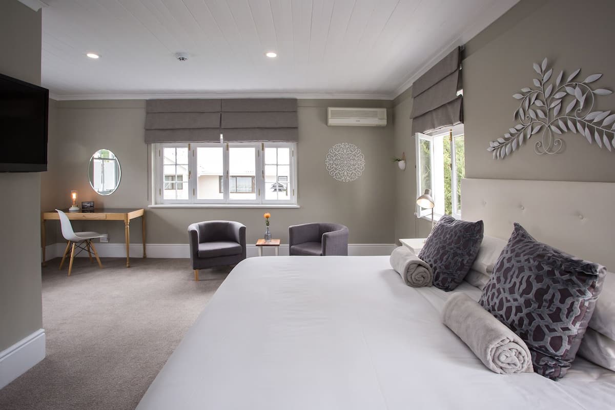 Ein Schlafzimmer mit einem großen Bett, einem Schreibtisch, zwei Stühlen, einem Spiegel und einer Wanddekoration.