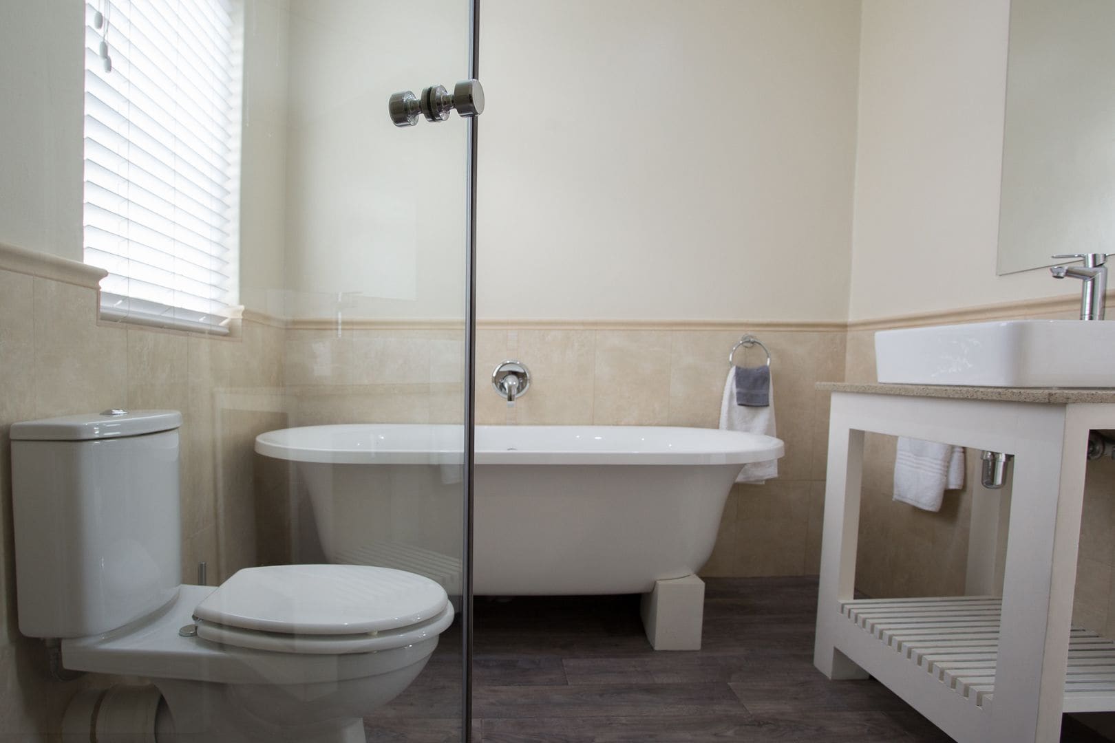 A bathroom with a glass-enclosed shower, a white toilet, and a sink with a mirror above it.