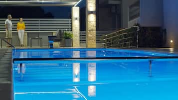 Een seizoensgebonden buitenzwembad, ligstoelen bij het zwembad