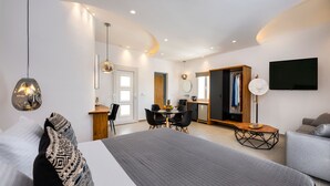 A modern bedroom with a large bed, a dining area, and a TV.