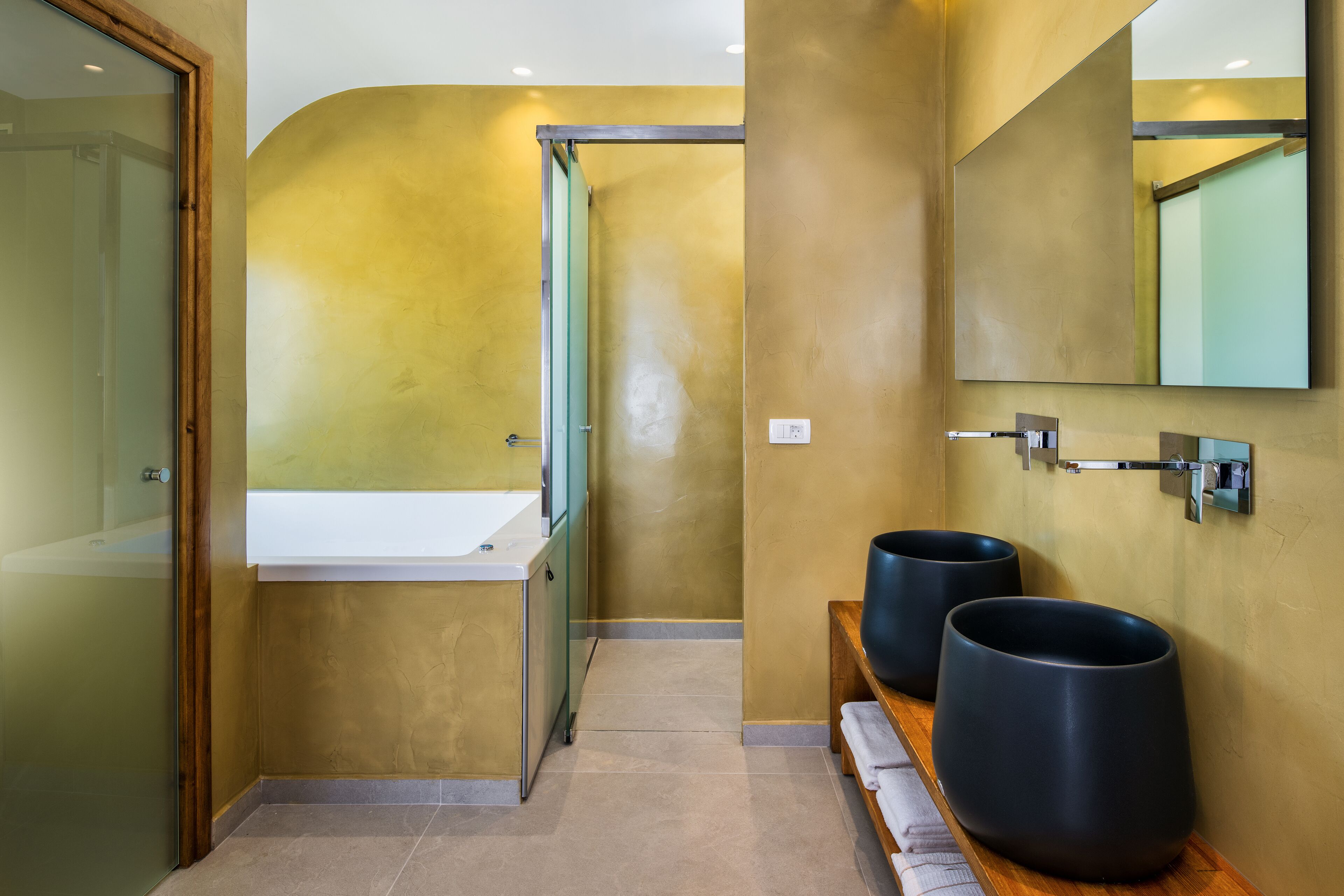 A modern bathroom with a large mirror, a sink, and two black basins.