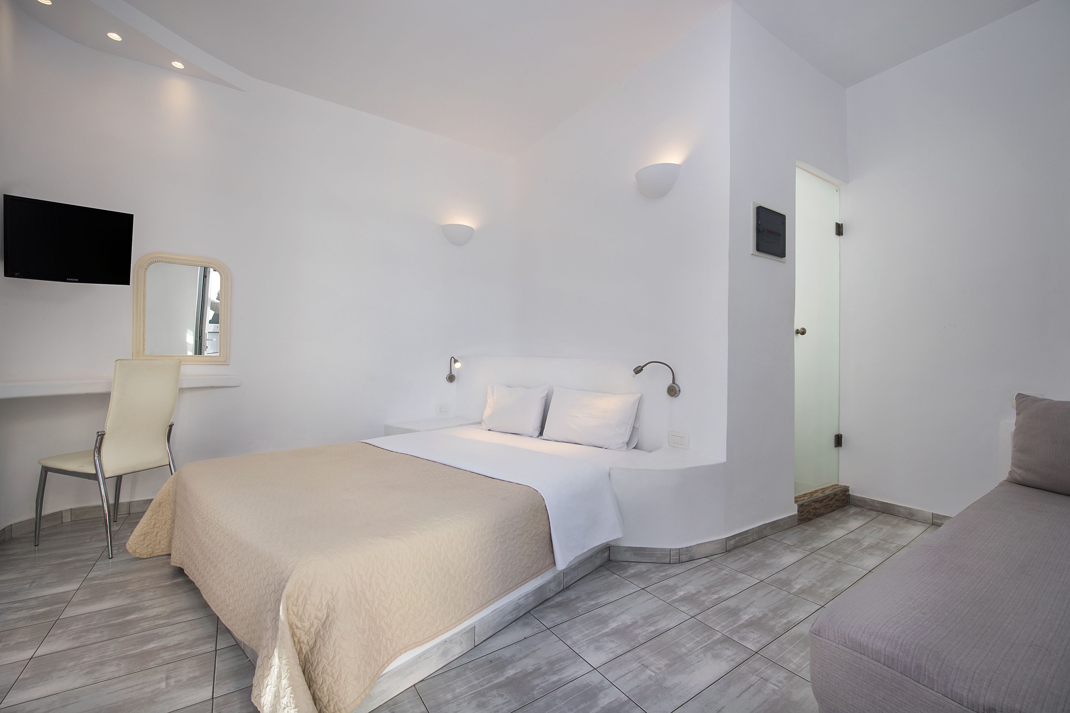 A modern bedroom with a bed, a chair, a TV, and a door.