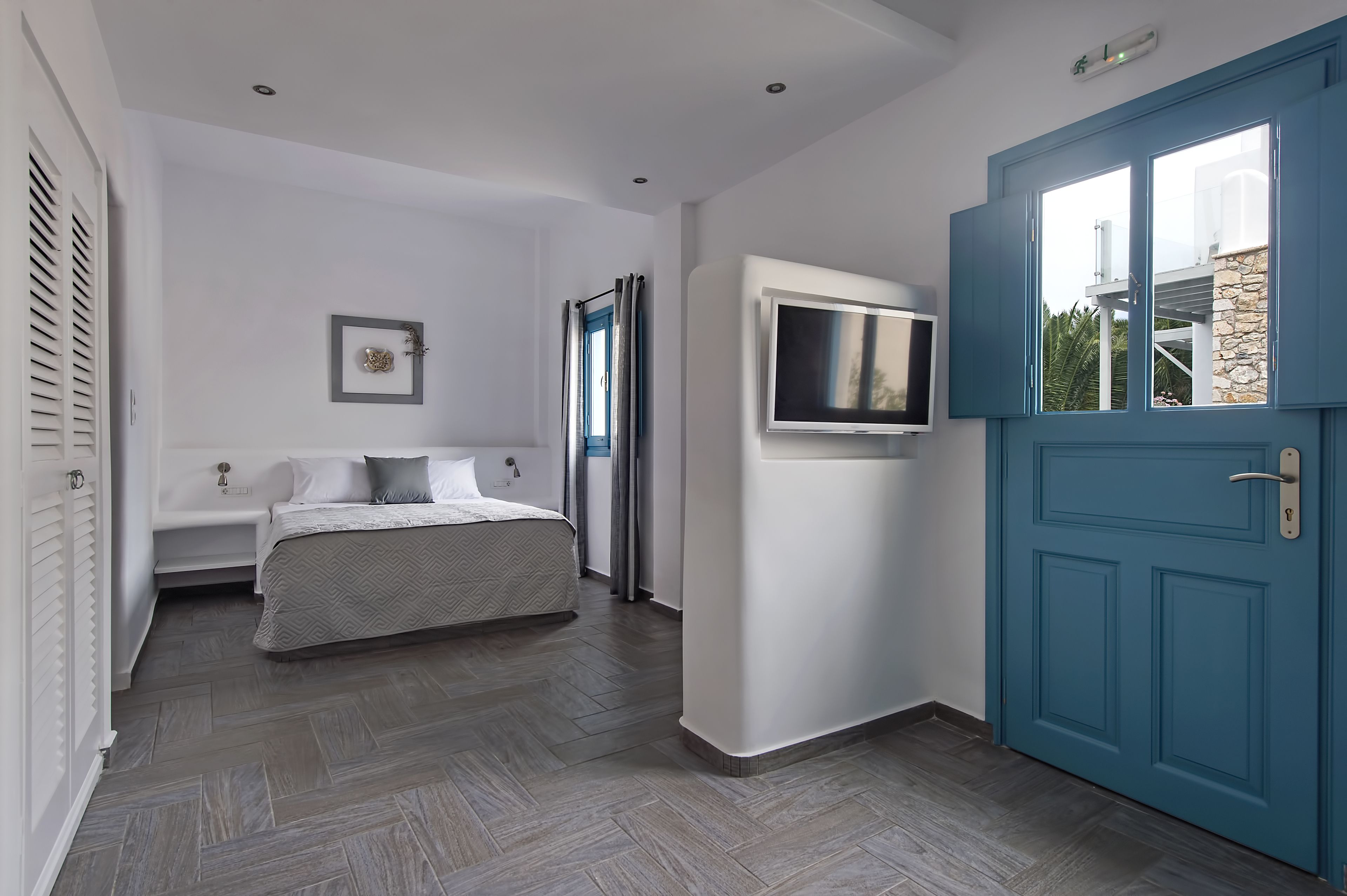 Un dormitorio con cama, televisor y puerta azul.