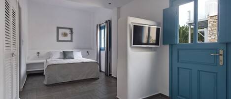 Un dormitorio con cama, televisor y puerta azul.