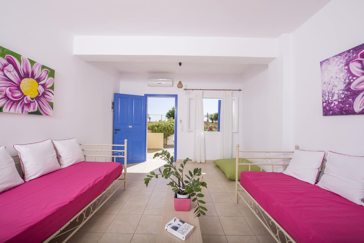 A room with two beds, a potted plant, and a door leading outside.