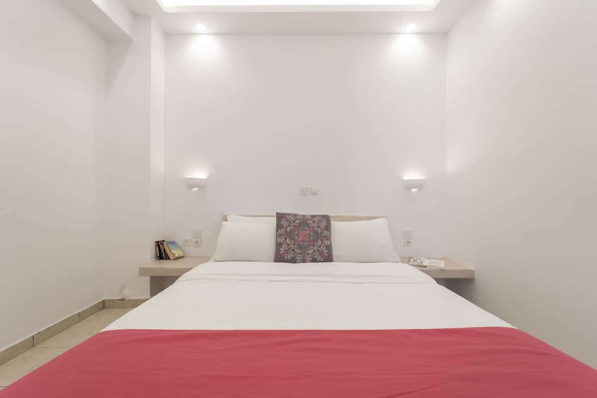 A bedroom with a bed, bedside tables, and a ceiling light.