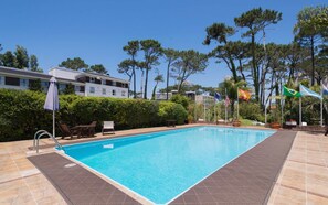 Una piscina al aire libre, sillones reclinables de piscina