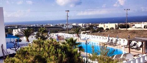 Uma área de piscina com espreguiçadeiras e vista para o mar.