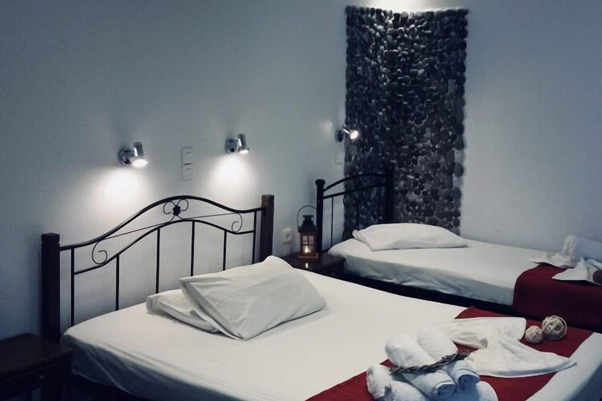 A hotel room with two beds, a stone wall, and a small table with a lantern.