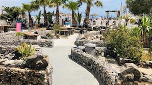 Uma área de resort com um calçadão pavimentado, palmeiras e muros de pedra.