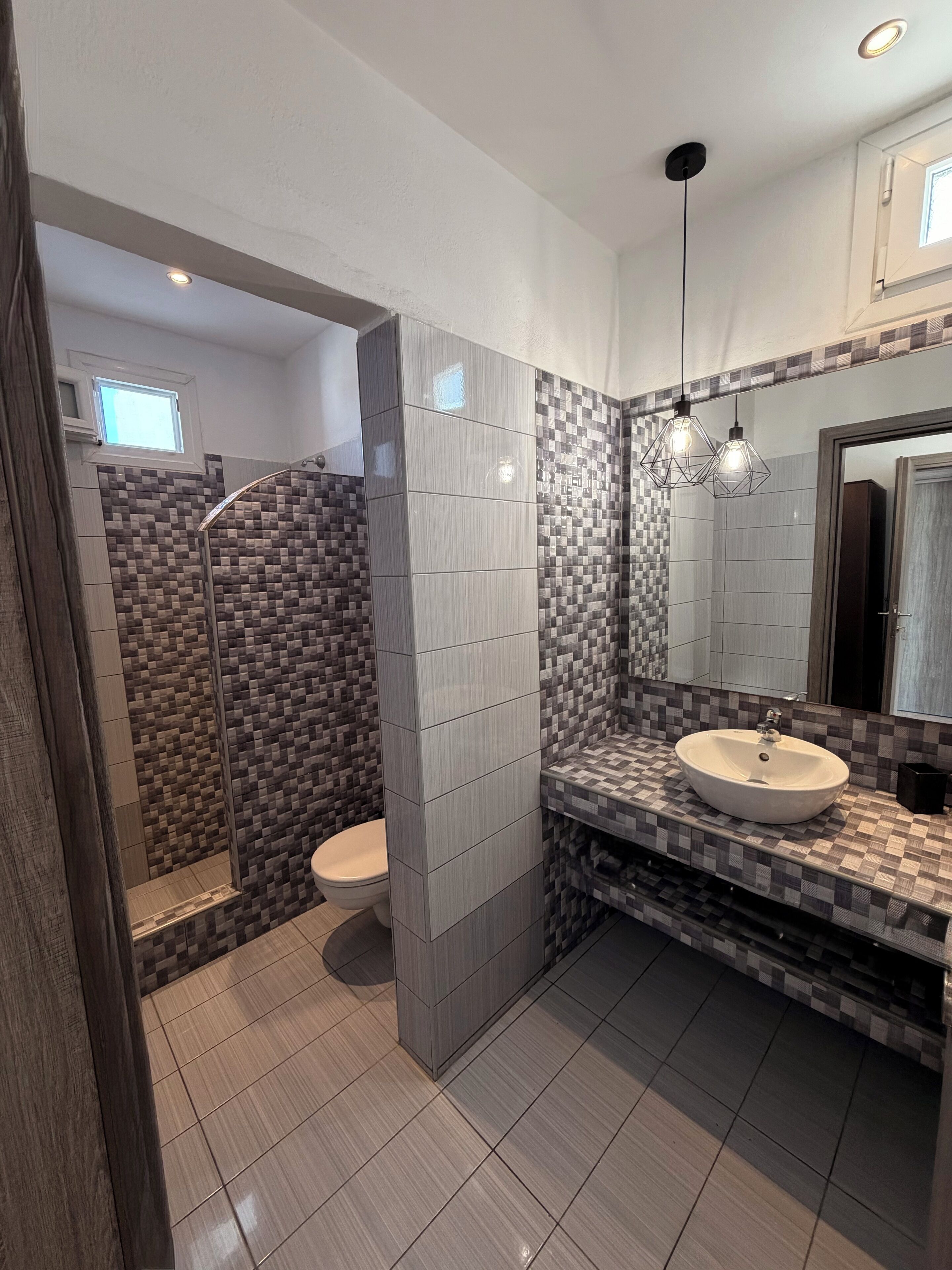 Un baño moderno con ducha, inodoro y tocador con lavamanos.