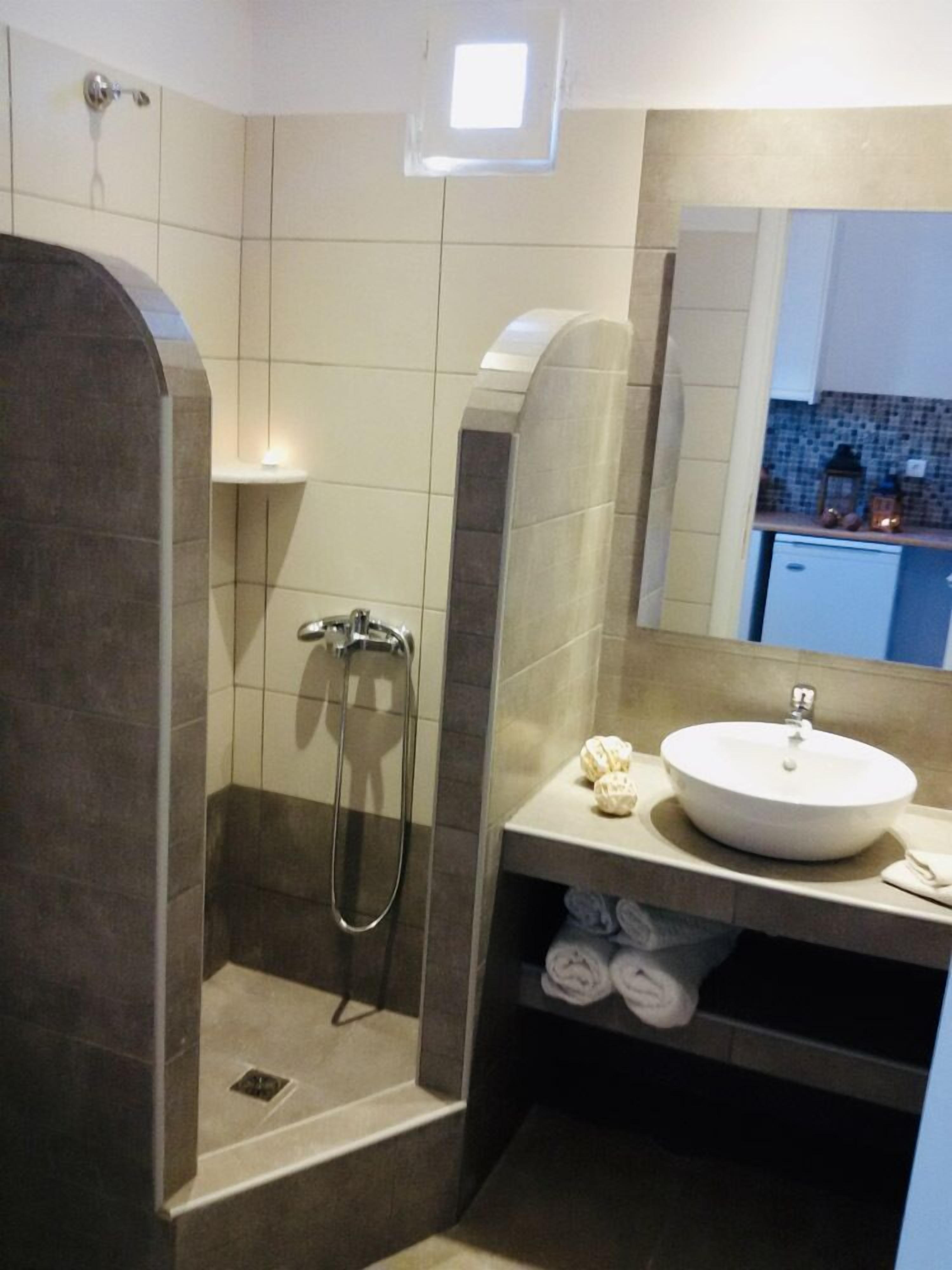 A modern bathroom with a walk-in shower, a sink with a mirror, and a towel rack.