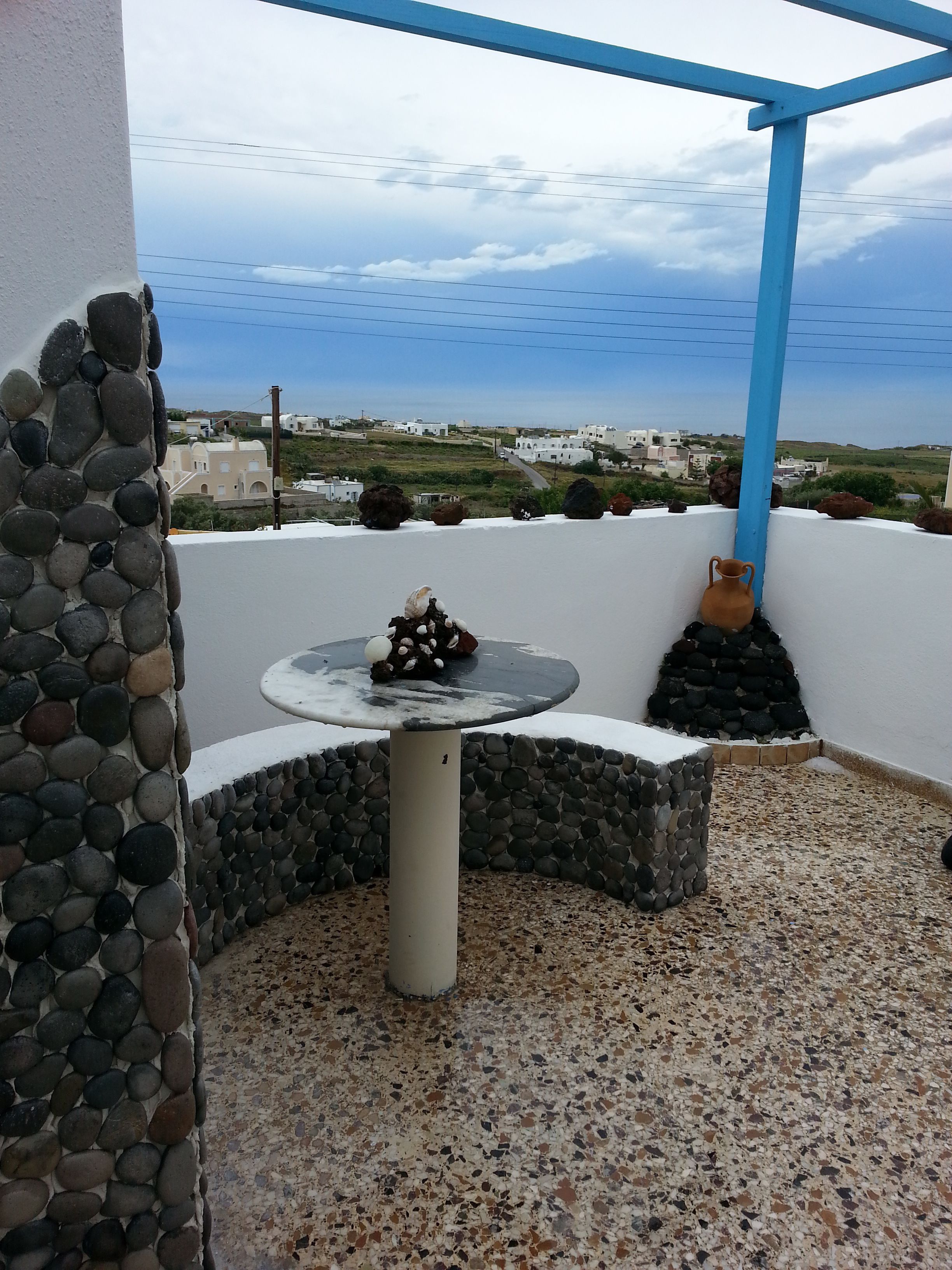 Un muro de piedra con una mesa y un florero en una terraza.