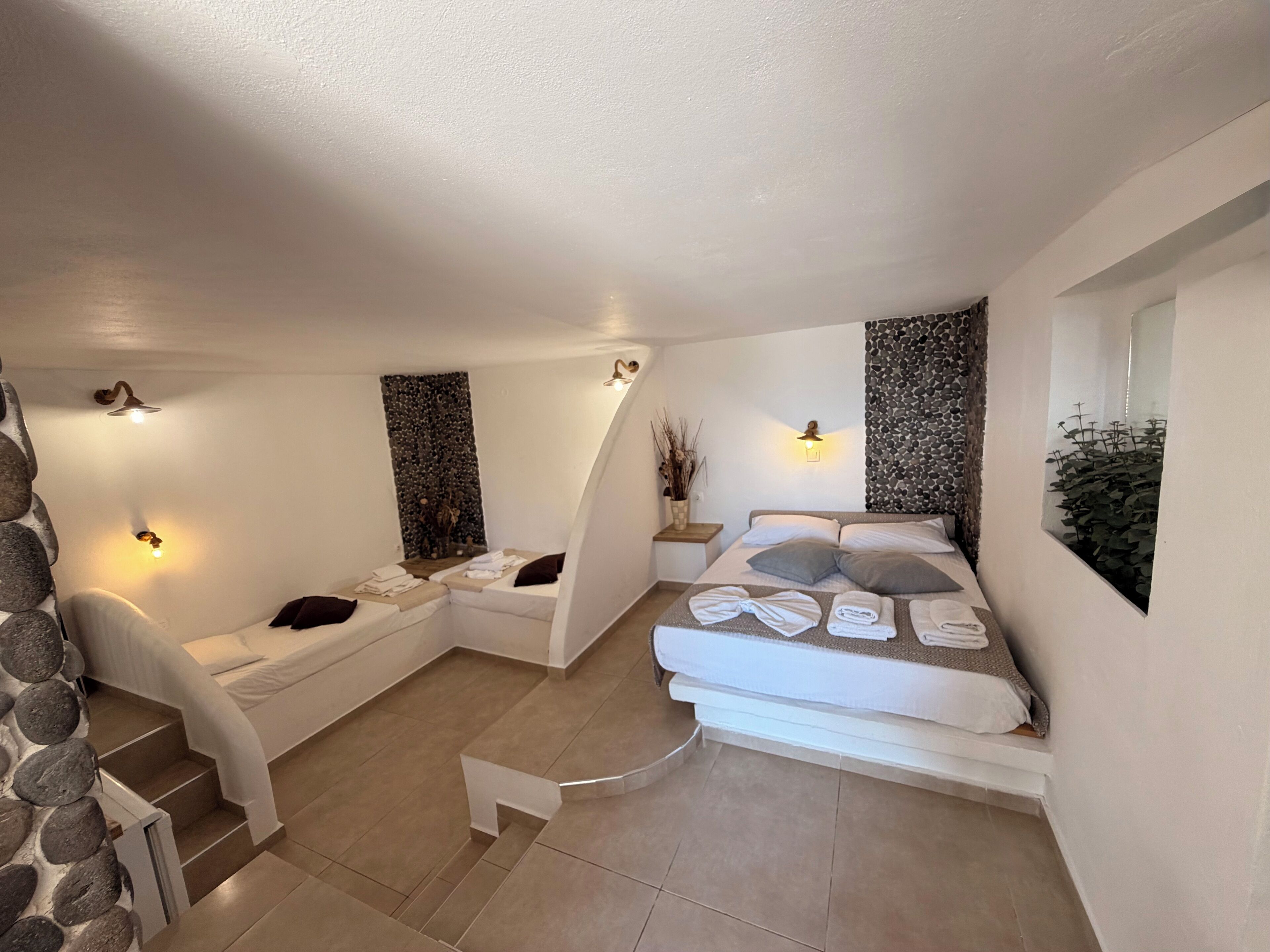 A spa room with a massage table, a small seating area with towels, and a stone wall.