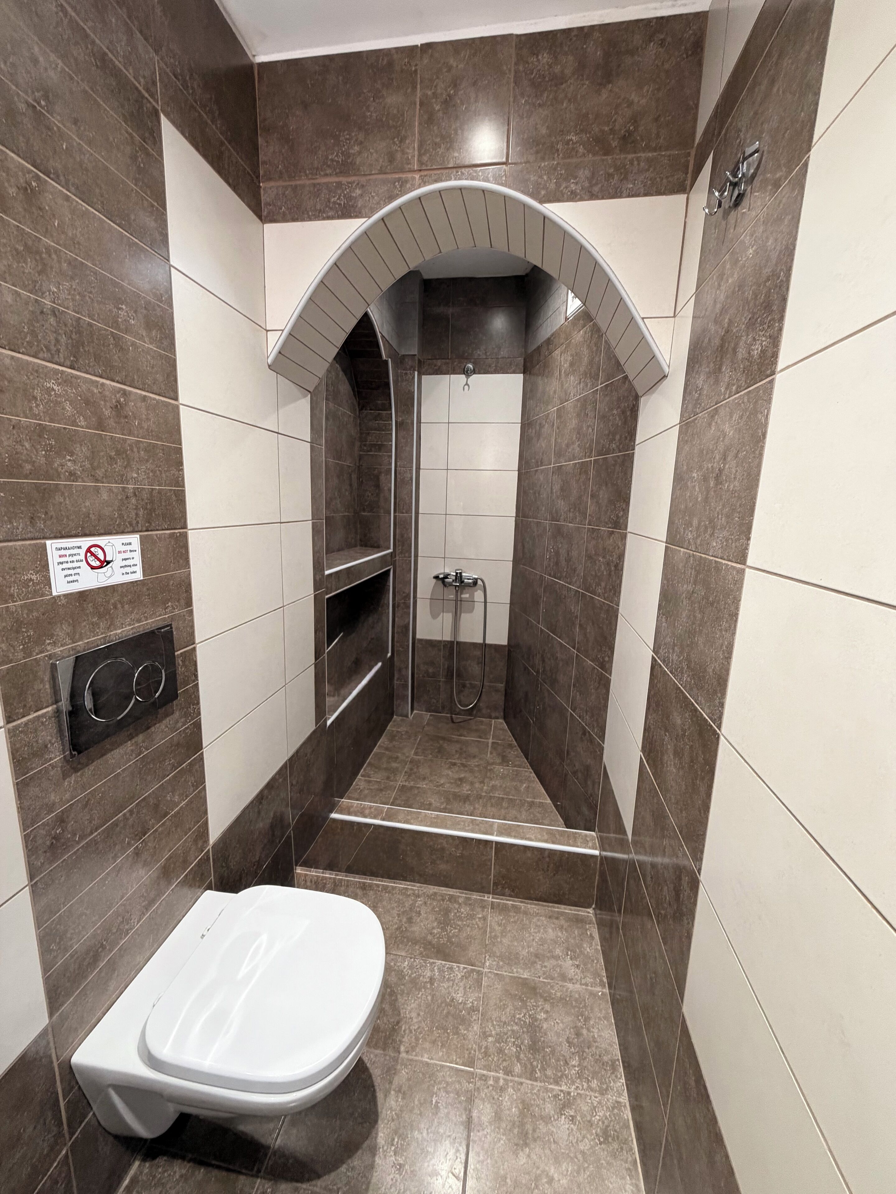Ein Badezimmer mit Dusche, Toilette und einem Schild an der Wand.