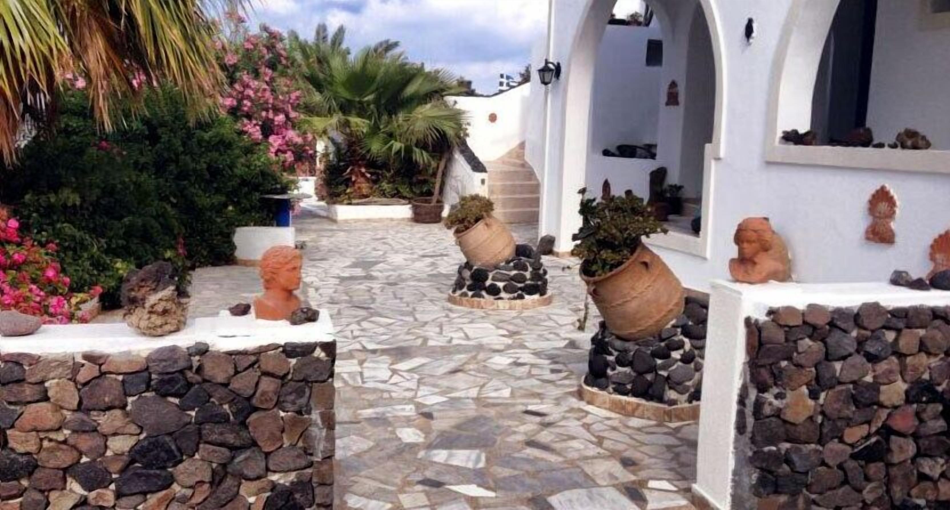 Un patio con piso de mosaico, paredes de piedra y plantas en macetas.