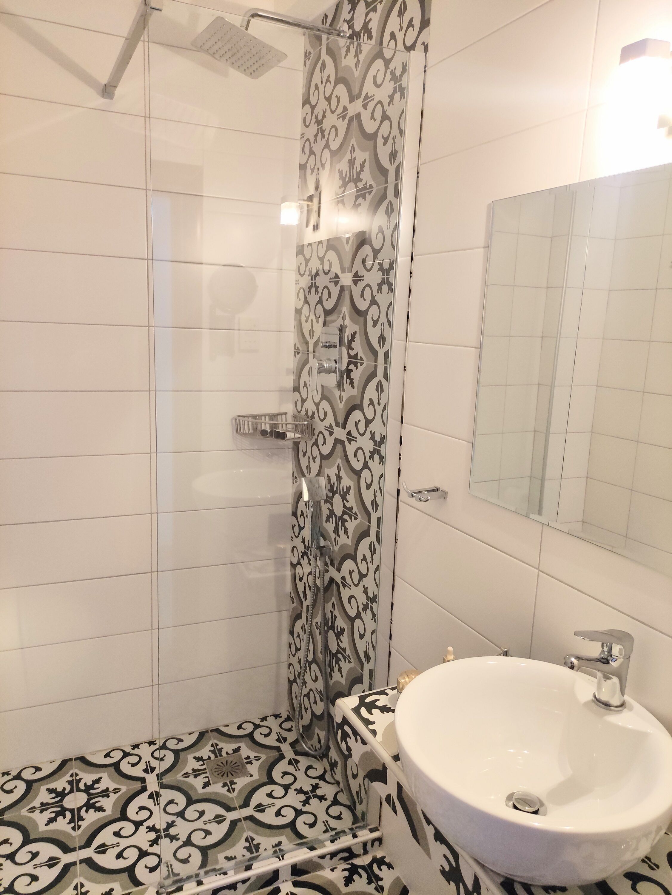 Un bagno con doccia, lavandino e specchio.