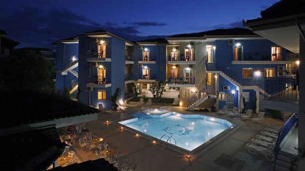 Un hotel de varios pisos con piscina, mobiliario exterior y balcones.