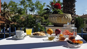 Una mesa dispuesta para el desayuno, con jugo de naranja, galletas, frutas y una taza de café.