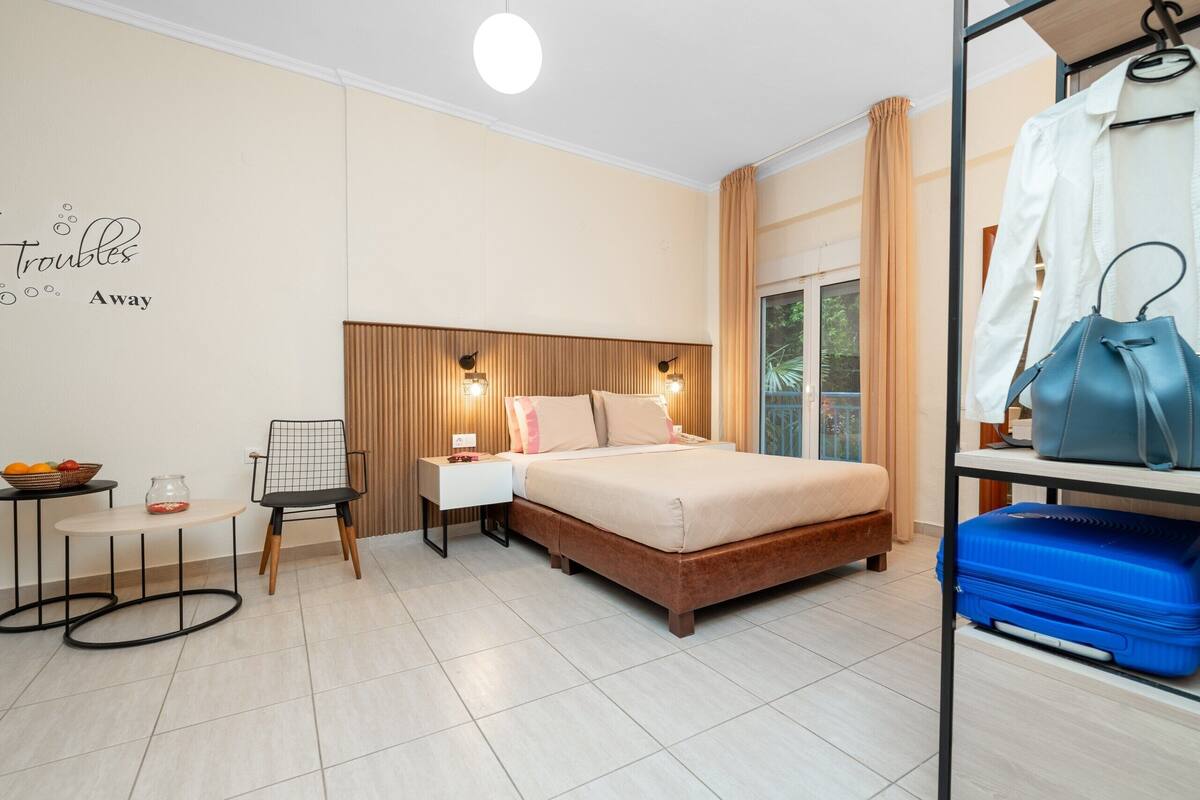 A hotel room with a bed, bedside table, chair, and a view of the outdoors.