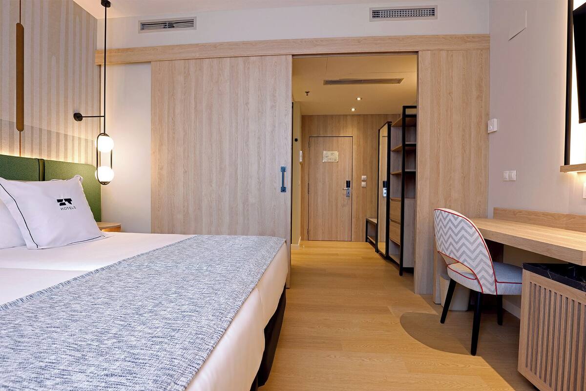 Ein Hotelzimmer mit Bett, Schreibtisch, Stuhl und Kleiderschrank.
