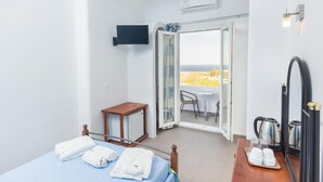 Habitación de hotel con cama, una mesita, una silla, cafetera y vista al mar.