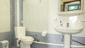Un baño con inodoro, lavamanos y paredes con azulejos.