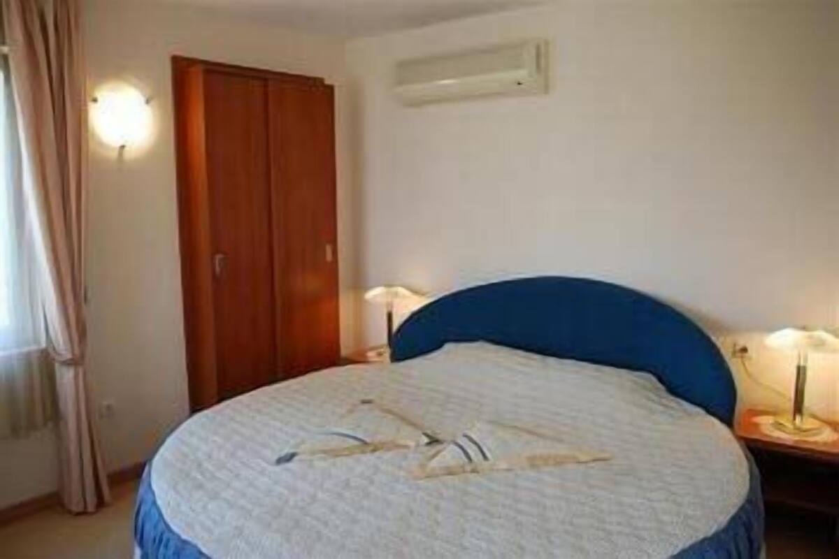 A bedroom with a bed, a wardrobe, and two bedside lamps.