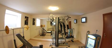 A gym with exercise equipment, a bench, a weight rack, and a vending machine.