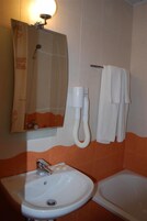 Un baño con lavamanos, espejo, toallero y ducha.