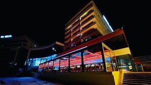 En moderne bygning med en glasfacade og en træterrasse foran.