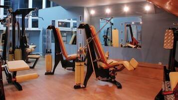 Una palestra con diverse macchine per esercizi, panche e una parete con specchi.