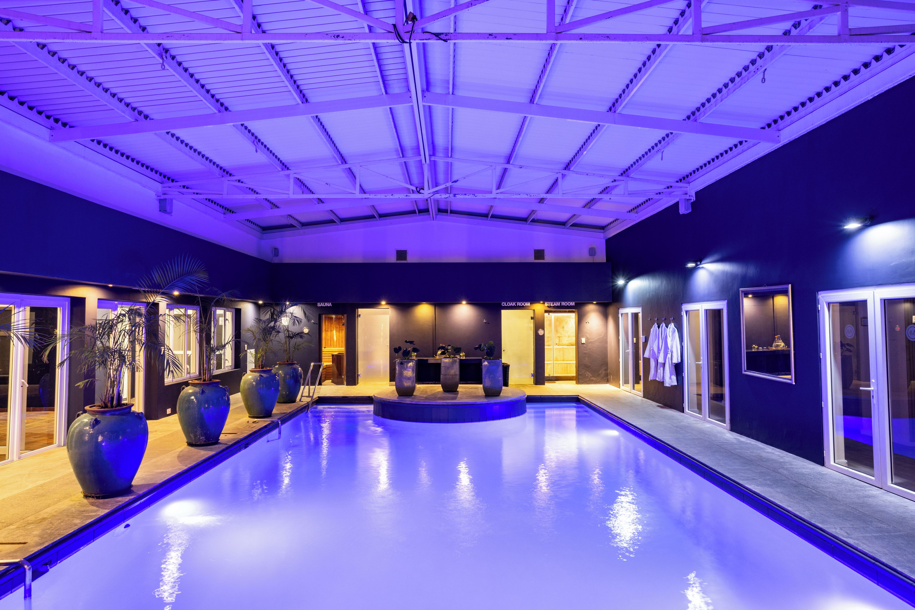 Ein großes Hallenbad mit einer Deckenkonstruktion, umgeben von Wänden mit Türen und Fenstern.