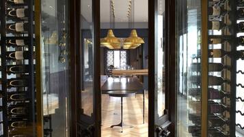 An interior view of a wine cellar with glass doors and shelves of wine bottles.