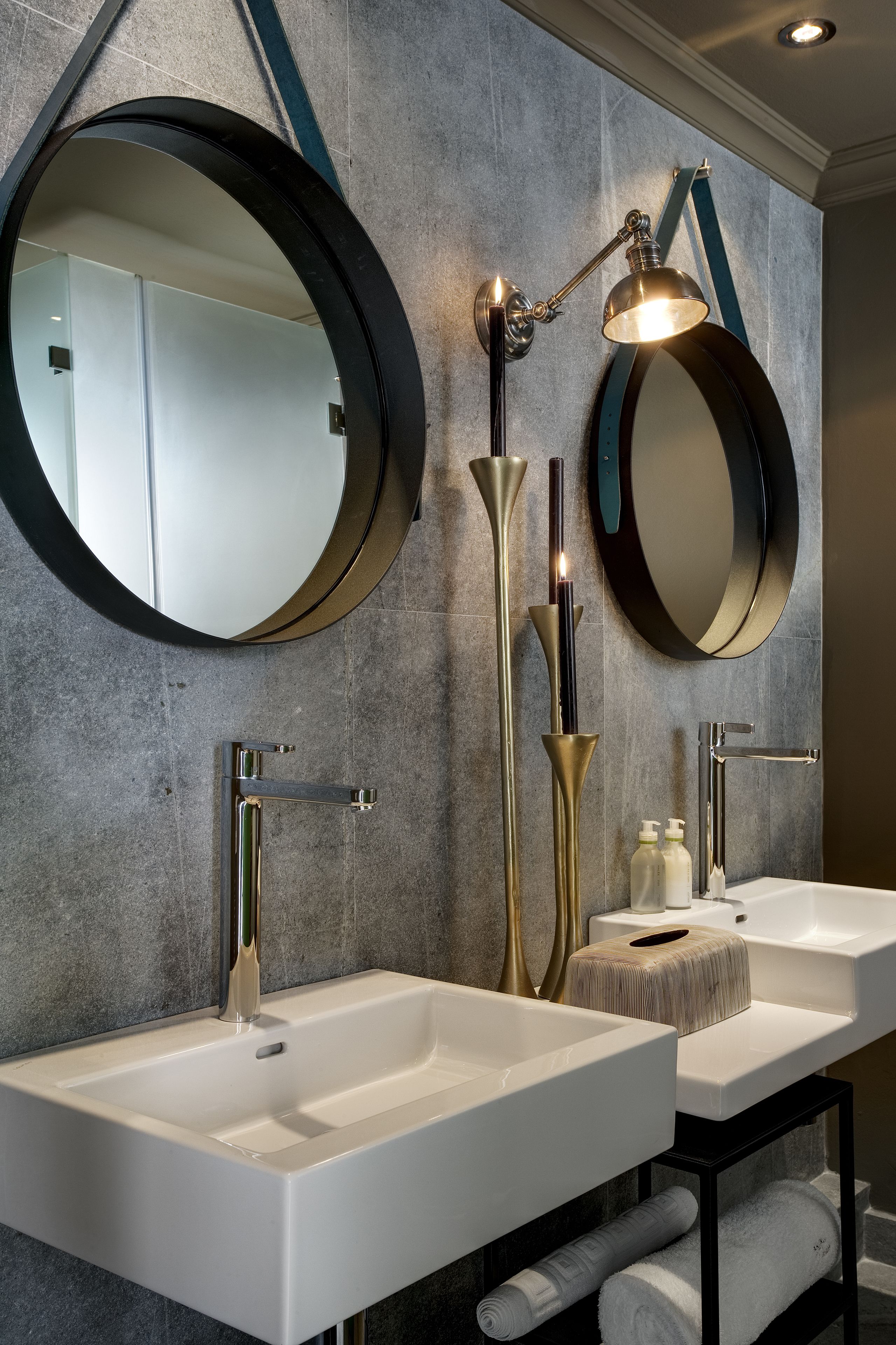 Une salle de bain moderne avec deux vasques, un grand miroir et un luminaire fixé au mur.