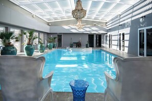 An indoor swimming pool with clear blue water, surrounded by large potted plants and modern chairs. - Majeka House Boutique Hotel (Stellenbosch)